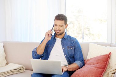 Evdeki kanepede otururken bilgisayarını kullanan yakışıklı bir gencin portresi.. 