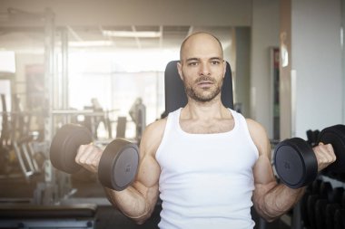 Atış daha kaslı vücut oluşturmak için dumbbell egzersizleri yapıyor spor salonunda adamın.