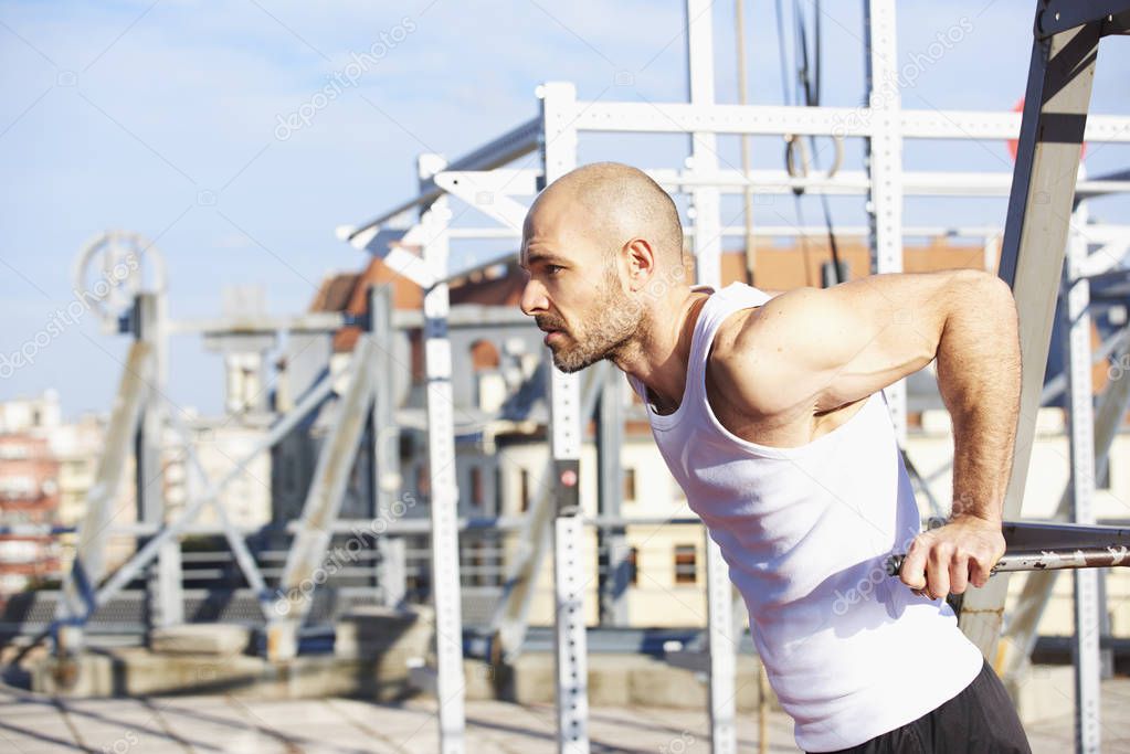 Shot of an athlete man doing exercises in the outdoor gym. 