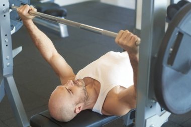 Adam yapıyor halter salonunda daha kaslı vücut oluşturmak için yüksek açı çekim.