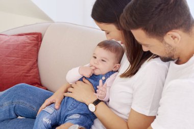 Mutlu genç aile oturan Divan bebek kızları ile vurdu ve evde rahatlatıcı keyfini çıkarın. 