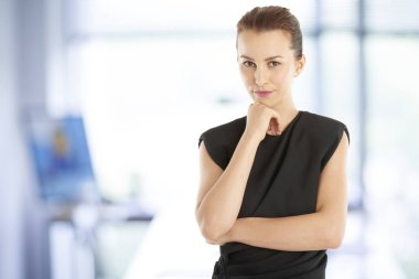 Bir düşünme genç iş kadını ofiste onu çene ayakta el ile portresi. 