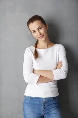 Çekici bir genç kadın gri duvar geçti silah ile ayakta stüdyo çekim.