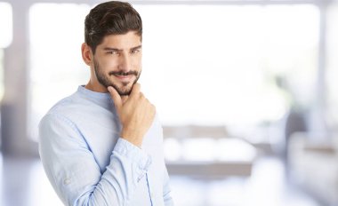 Kameraya bakarak ve gülümseyen kapalı duran çene üzerinde el ile genç bir adam çekim. 