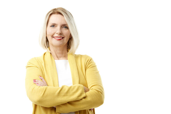 Studio shot of a happy mature woman standing with arms crossed at isolated white background with copy space.