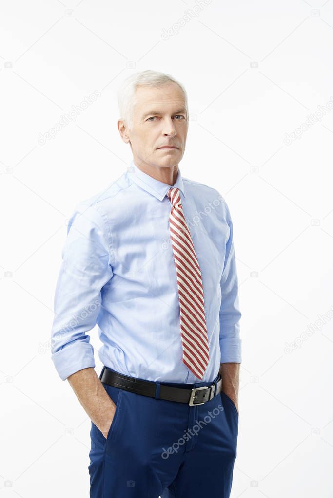 A handsome senior man wearing rolled up sleeve shirt and tie while standing at isolated white background.