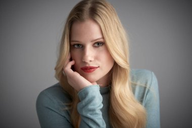 Yakın çekim stüdyo portre düşünme genç kadının gri arka plan poz kameraya bakıyor. 