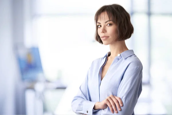 Привлекательная деловая женщина, стоящая со сложенными руками в офисе — стоковое фото