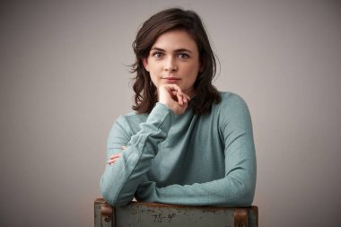 Güzel gülümseyen genç kadın el ile onu çene üzerinde oturuyor c