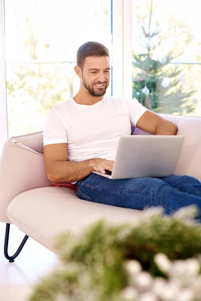 Portret shot van knappe jonge man browsen op laptop terwijl zitten — Stockfoto