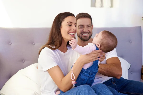 Feliz joven familia sentada en el sofá con su bebé y havi — Foto de Stock