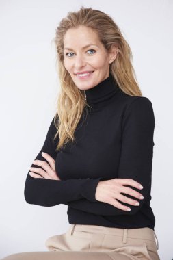 Portrait shot of attractive middle aged woman looking at camera and smiling while sitting at isolated white background. clipart