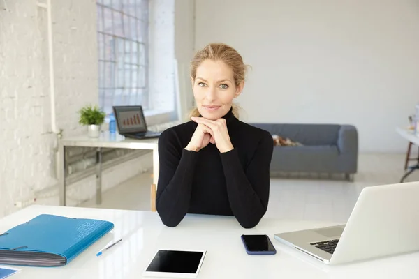 Attractive mature businesswoman sitting at office desk while loo