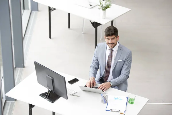 Elegante asesor de inversión hombre de negocios utilizando su computadora portátil en el o —  Fotos de Stock