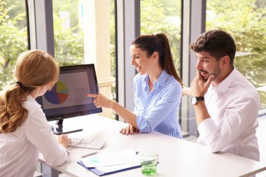 Finansal danışman iş kadını ofis masasında bilgisayarın önünde oturuyor ve genç çifte finansal ipuçları hakkında danışmanlık yapıyor..
