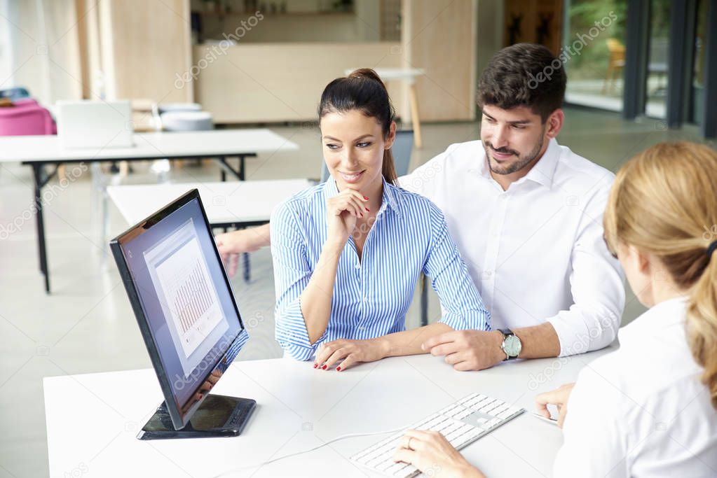 Financial advisor businesswoman sitting at office desk in front of computer and consulting with young couple about finance ideas.