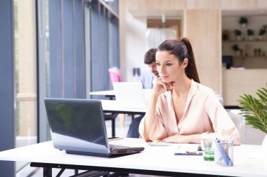 Ofiste dizüstü bilgisayarla çalışan bir iş kadını. 