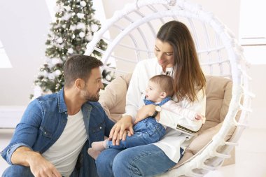 Gülümseyen genç aile, sevimli bebek kızlarıyla vakit geçirmekten zevk alır.