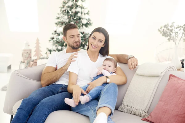 Evdeki kanepede dinlenen küçük kızlarıyla güzel bir aile.