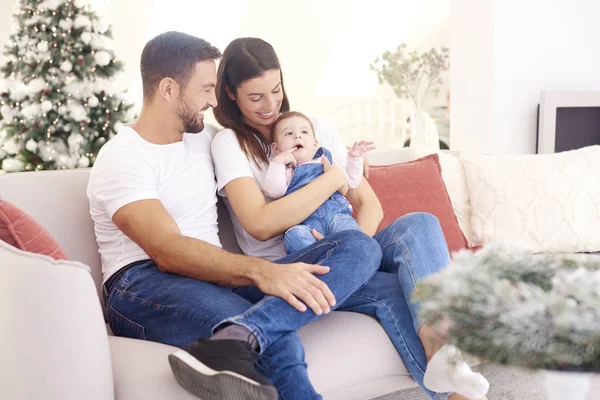 Lovely family with their baby girl relaxing on sofa at home duri — Stock Photo, Image
