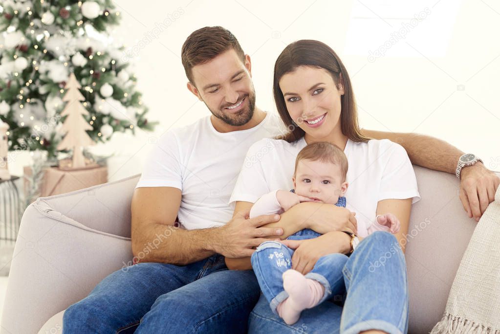 Lovely family with their baby girls relaxing on sofa at home 