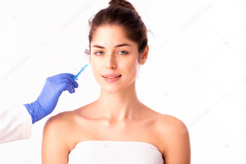 Portrait shot of an attractive woman receiving botox treatment for prevention. Isolated on white background. 