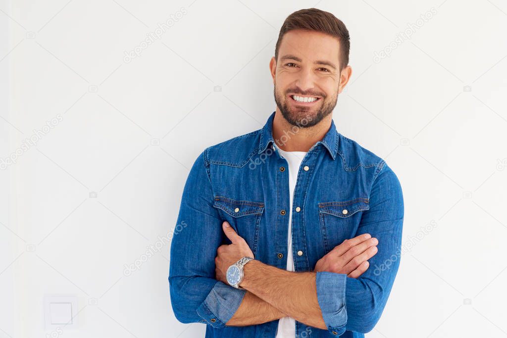 Close-up portrait of handsome young man looking at camera and smiling while wearing casual clothes and standing at isolated white background. 