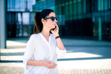 Çekici bir kadının sokakta yürürken telefon görüşmesi yaptığı yakın çekim.. 