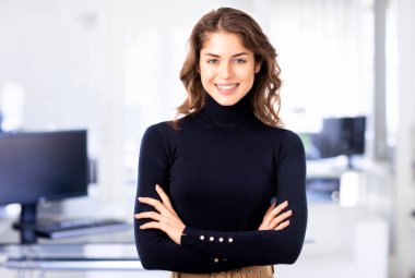 Ofiste kollarını kavuşturmuş gülümseyen güzel bir iş kadınının portresi..