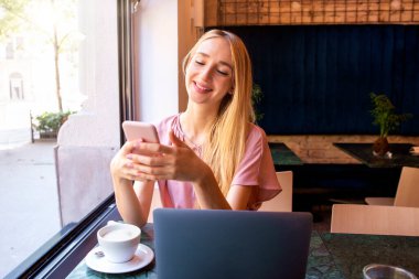 Kafede mutlu bir günde genç bir kadının mesajlaşması ve kahve keyfi yapması.. 