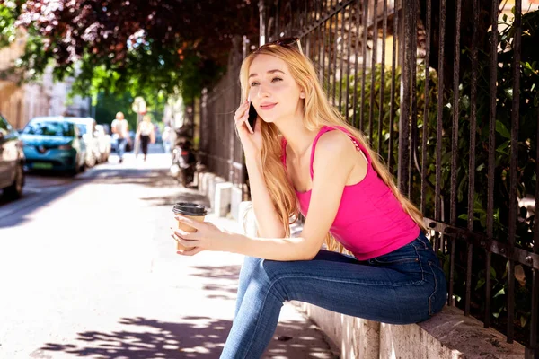 Портрет Улыбающейся Девушки Сидящей Улице Телефоном Пьющей Кофе — стоковое фото