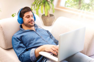 Evde müzik dinlerken, kulaklık takan yakışıklı bir gencin fotoğrafı.. 