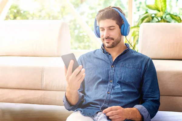 Tiro Hombre Guapo Sonriente Con Auriculares Relajándose Sofá Usando Teléfono —  Fotos de Stock