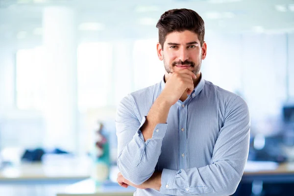 Ofiste kameraya bakıp gülümserken elleri çenesinde duran kendine güvenen iş adamının stüdyo fotoğrafı.. 