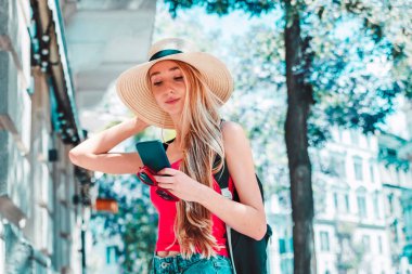 Sokakta durup mesajlaşırken hasır şapka takan güzel bir genç kadının yakın plan portresi..