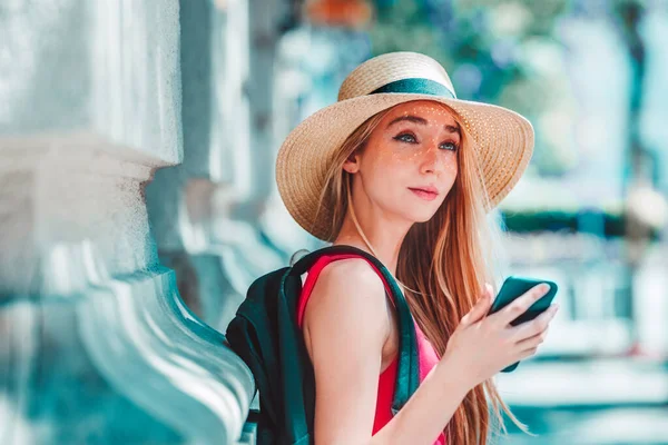 Sokakta durup mesajlaşırken hasır şapka takan güzel bir genç kadının yakın plan portresi..