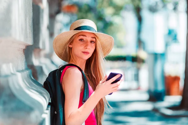 Sokakta durup mesajlaşırken hasır şapka takan güzel bir genç kadının yakın plan portresi..