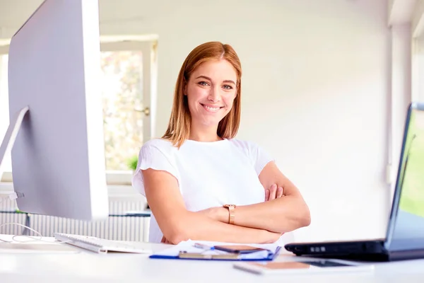 Schöne Lächelnde Junge Frau Mit Verschränkten Armen Die Schreibtisch Sitzt — Stockfoto