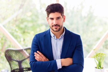 Ofiste kollarını kavuşturmuş dururken gömlek ve ceket giyen yakışıklı iş adamının portresi.. 