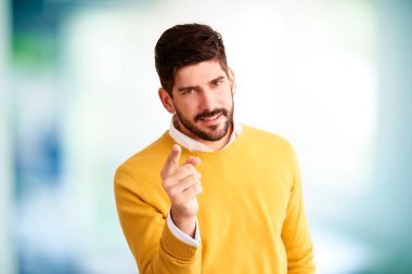 Genç işadamının stüdyo portresi parmağını size doğrultuyor ve kapalı alanda kameraya bakıyor.. 