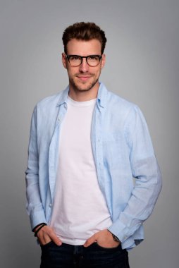 Tecrit edilmiş arka planda duran yakışıklı bir gencin stüdyo fotoğrafı. Tişört giyen ve kameraya bakan kendinden emin bir erkek. Uzayı kopyala İzole edilmiş arkaplan. 