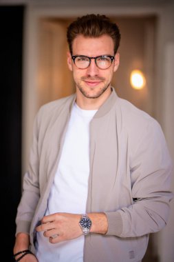 Kameraya bakıp gülümseyen genç bir adamın vesikalığı. Beyaz gömlek ve ceket giyen ve içeride duran kendine güvenen bir adam.. 