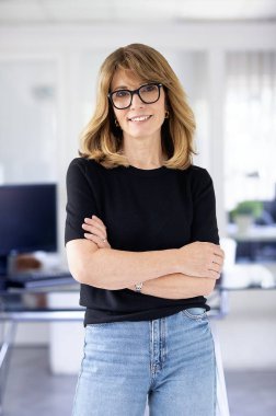 Ofiste kendine güvenen ve kameraya bakan bir iş kadını. Orta yaşlı profesyonel kadın iş kıyafeti giyiyor ve gülümsüyor. Boşluğu kopyala. 