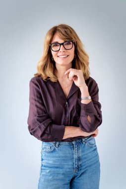 Sarışın kadın, izole edilmiş arka planda duruyor ve kameraya bakıyor. Gömlek ve kot pantolon giyen orta yaşlı bir kadın. Boşluğu kopyala. 