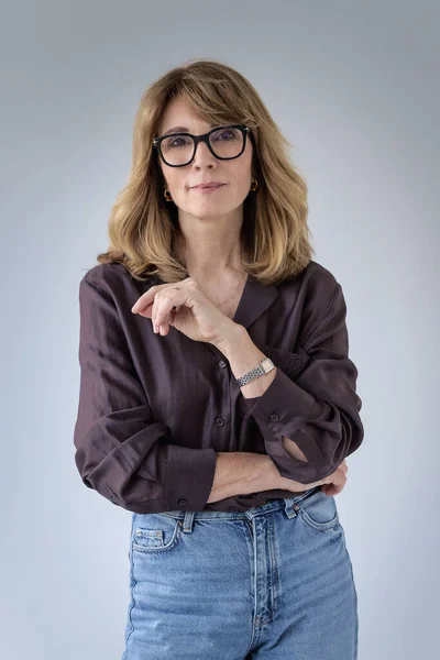 Sarışın kadın, izole edilmiş arka planda duruyor ve kameraya bakıyor. Gömlek ve kot pantolon giyen orta yaşlı bir kadın. Boşluğu kopyala. 