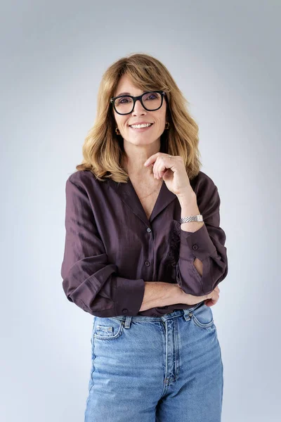 Sarışın kadın, izole edilmiş arka planda duruyor ve kameraya bakıyor. Gömlek ve kot pantolon giyen orta yaşlı bir kadın. Boşluğu kopyala. 