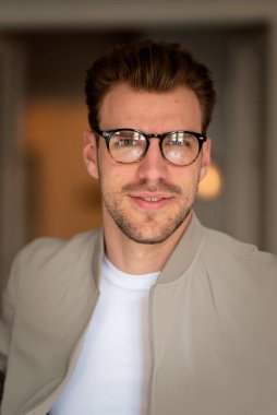 Kameraya bakıp gülümseyen genç bir adamın vesikalığı. Beyaz gömlek ve ceket giyen ve içeride duran kendine güvenen bir adam.. 