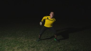 kaleci topu siyah bir arka planda yakalar.