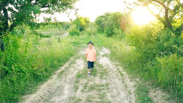 O menino está andando em uma estrada de terra — Vídeo de Stock