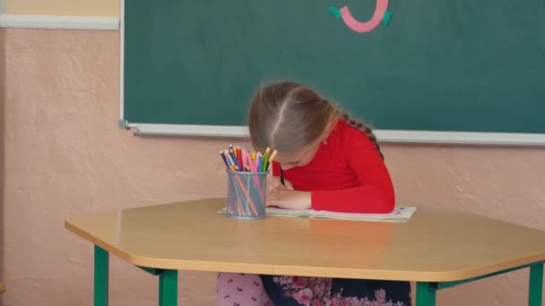 Маленька дівчинка щось малює — стокове відео
